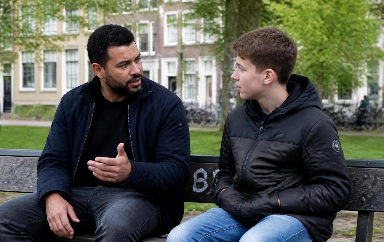 Een mentor en een jongen in gesprek op een bankje in de wijk