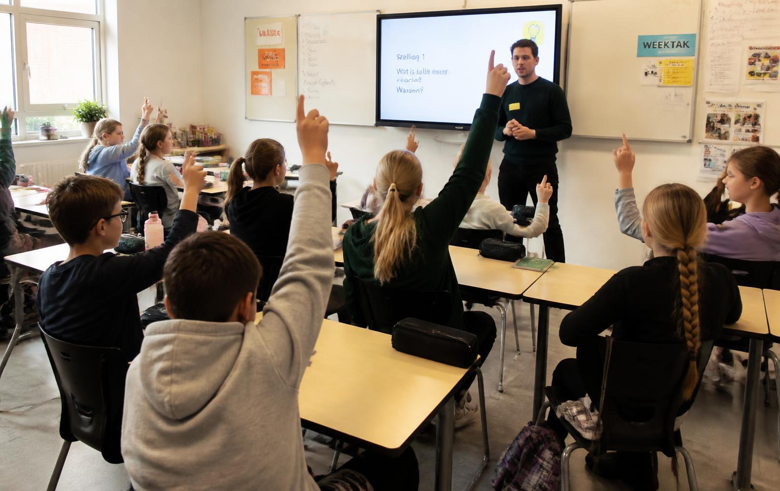 Leerlingen uit groep 8 steken hun hand op tijdens een interactieve workshop